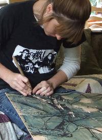 Sharon carving into the wood panel